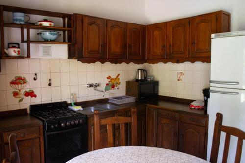 eine Küche mit Holzschränken, einem Herd und einem Kühlschrank in der Unterkunft Amplio chalet en zona centro in San José