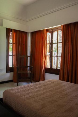 a bedroom with a bed and a chair and windows at Amplio chalet en zona centro San José, Entre Ríos in San José