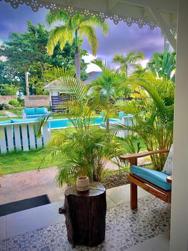 a patio with a bench and palm trees and a pool at PUNTA POPY BOUTIQUE HOTEL - Adults Only in Las Terrenas