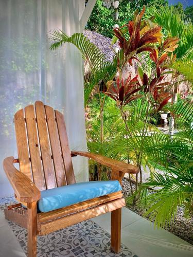 a wooden chair with a blue cushion sitting on a porch at PUNTA POPY BOUTIQUE HOTEL - Adults Only in Las Terrenas