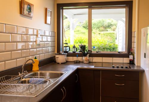 uma cozinha com um lavatório e uma janela em Halfmoon Cottage em Akaroa