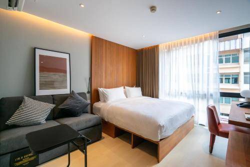 a hotel room with a bed and a couch at Woodstory Boutique Hotel in Bangkok