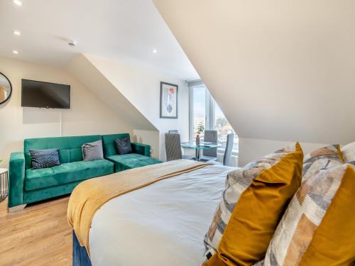 a bedroom with a bed and a green couch at Apartment Five - Uk44289 in Arbroath