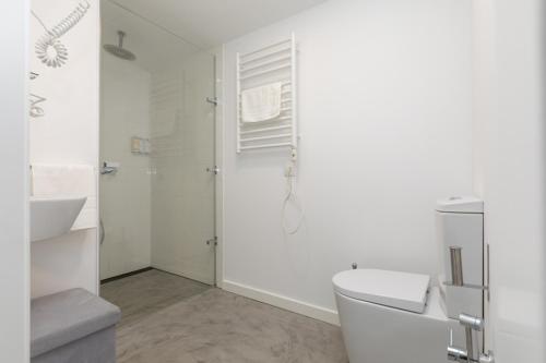 een witte badkamer met een toilet en een wastafel bij AveiNest - Your Studio in Aveiro in Aveiro