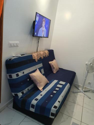 a couch in a room with a tv on a wall at Bungalow vacances in Sainte-Rose