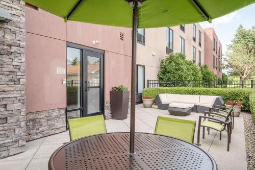 a table with a green umbrella on a patio at SpringHill Suites Terre Haute in Terre Haute