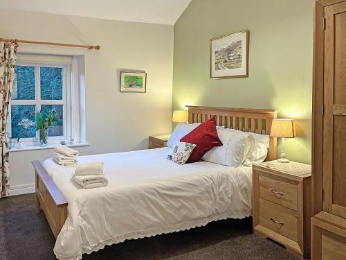 1 dormitorio con 1 cama con sábanas blancas y almohadas rojas en Bluebell Cottage en Garstang