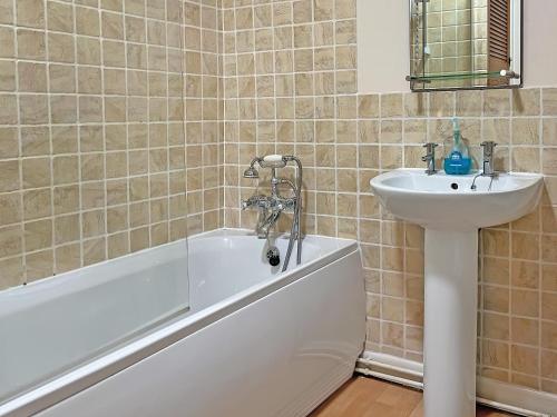 a bathroom with a bath tub and a sink at Bluebell Cottage in Garstang