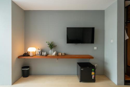 a living room with a television on a wall at Woodstory Boutique Hotel in Bangkok