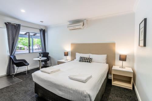 Un dormitorio con una gran cama blanca y una ventana en Manjimup Kingsley Motel, en Manjimup