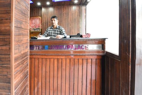 un hombre sentado en un bar en un restaurante en OYO Hotel Jammu Palace, en Jammu