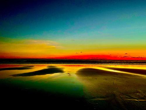 a sunset on the beach with a reflection in the water at Beachfront Paradise in Manuel Antonio