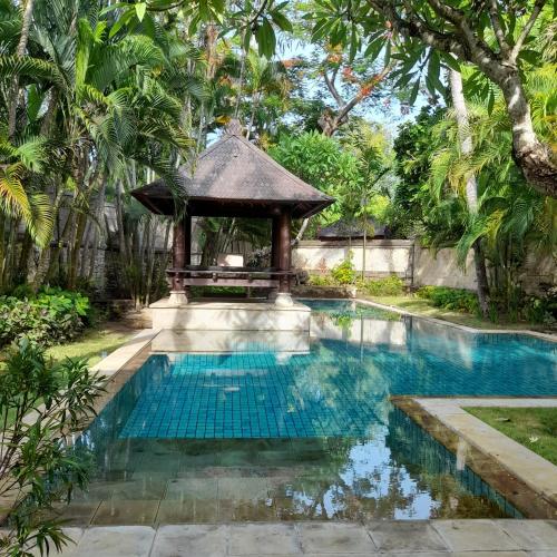 a swimming pool with a gazebo in a garden at The Royal Beach Seminyak Bali in Seminyak