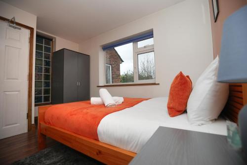 a bedroom with a large bed with an orange blanket at Contractors - Relocators - Family in Loughborough