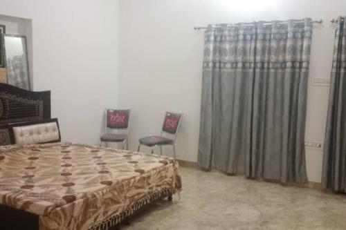 1 dormitorio con 1 cama y 2 sillas en Salasar Sadan, en Bikaner
