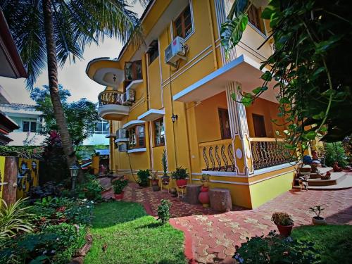 a yellow house with a balcony and a yard at Minria Guest House in Benaulim