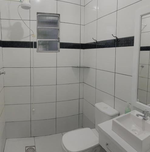 a white bathroom with a toilet and a sink at Casa cinza in São Lourenço do Sul