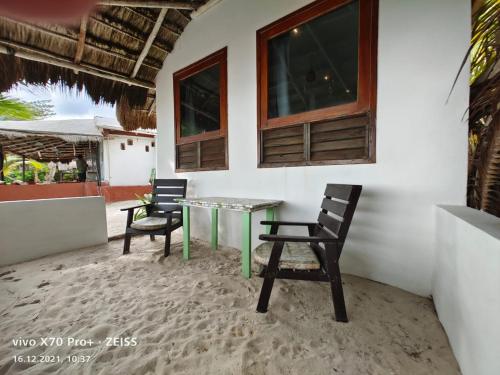 eine Terrasse mit 2 Stühlen und einem Glastisch in der Unterkunft Lunazul Eco-Cabaña Frente al Mar in Mahahual