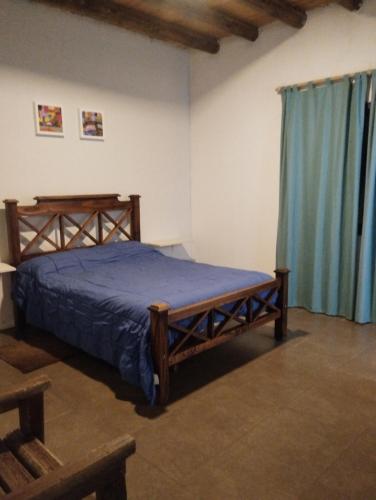 1 dormitorio con cama de madera y manta azul en El Coiron en Colonia Las Rosas