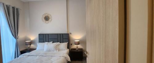 une chambre avec un grand lit avec des draps et des oreillers blancs dans l'établissement Ensuite one bedroom in a 2-bedroom with a shared living room, à Dubaï