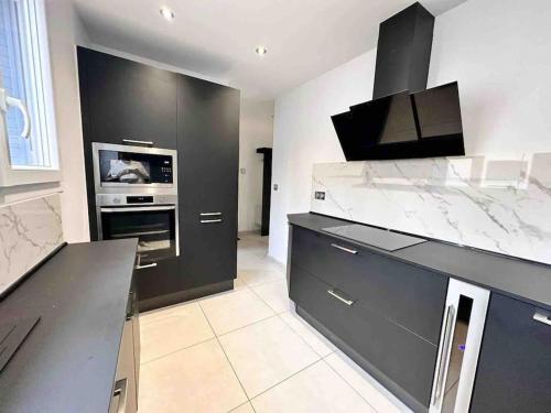 a kitchen with black cabinets and a stove at Le Victor Hugo - SPA in Nevers