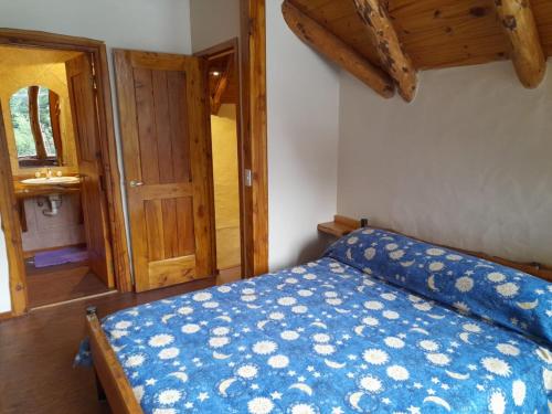 Schlafzimmer mit einem Bett mit blauer Decke in der Unterkunft Cabaña El Viaje in San Carlos de Bariloche