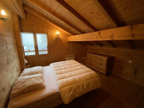 a bedroom with a bed in a wooden cabin at Chalet cosy 9 pers, 100m des pistes et 300m des commerces, avec WIFI et balcon sud-ouest - FR-1-733-152 in Crest-Voland