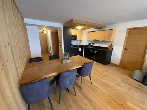une cuisine et une salle à manger avec une table et des chaises en bois dans l'établissement Spacieux et Moderne Appartement de 67m² à La Chapelle-d'Abondance, Balcon Exposé Ouest - FR-1-692-94, à La Chapelle-dʼAbondance