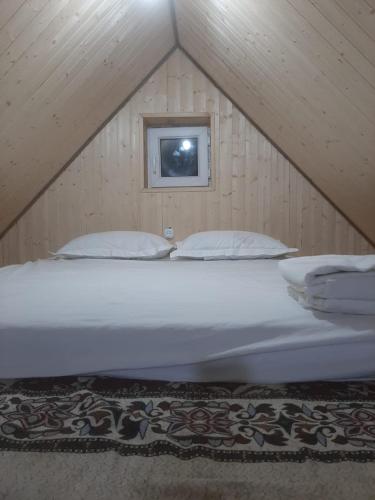 a large white bed in a attic with a window at Eldos_Kolsai in Saty