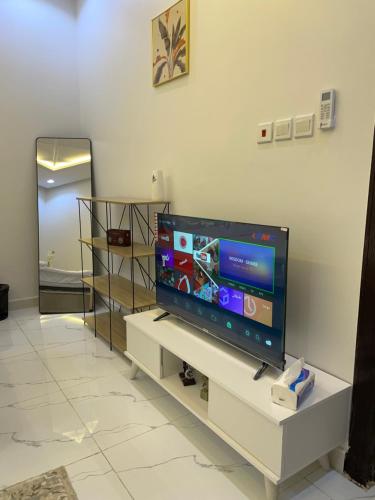 uma televisão de ecrã plano sentada num centro de entretenimento branco em استديو em Riyadh