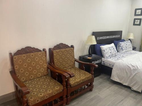 a bedroom with a bed and a chair and a bed at Grey Orchard Homestay - A Family Place in Lahore