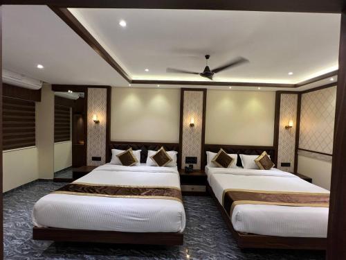 a hotel room with two beds and a ceiling fan at Hotel Mangalore Stay INN in Mangalore