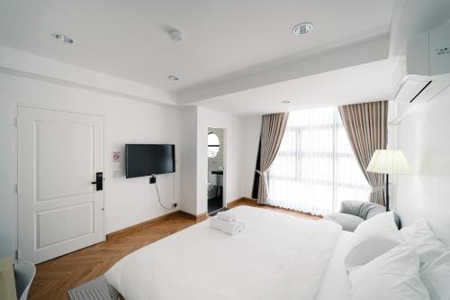 a white room with a bed and a tv at Mitt Haus (Lat Phrao Soi 5) in Bang Su