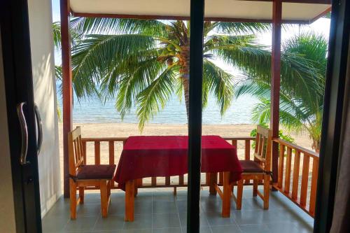 una mesa y sillas en un balcón con vistas a la playa en The Scenery Beach Resort, en Baan Khai