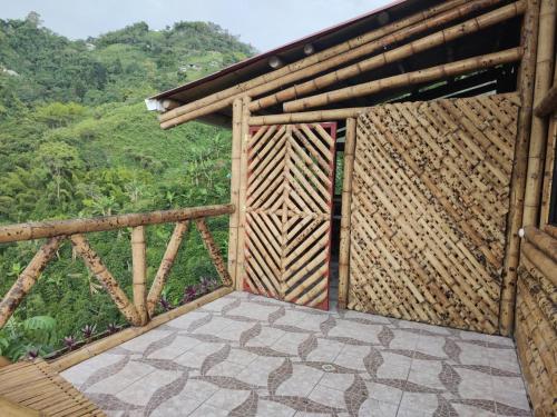 una porta aperta in legno su un balcone con vista su una foresta di La Cabaña de Bambú a Manizales
