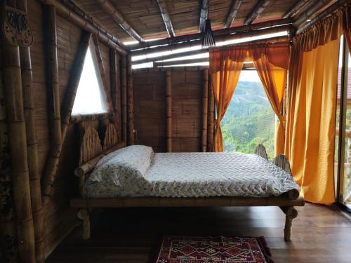 a bedroom with a bed in a room with windows at La Cabaña de Bambú in Manizales