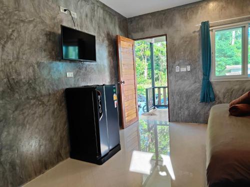 a kitchen with a refrigerator and a tv on a wall at Baanchomjan Kohyaoyai in Ban Nai Wat