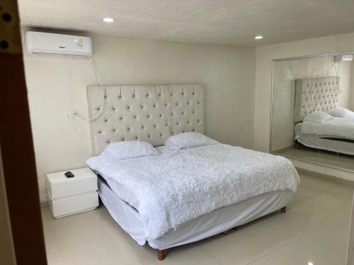 a white bedroom with a large bed and a mirror at La casa de Mickey in Ciudad Juárez