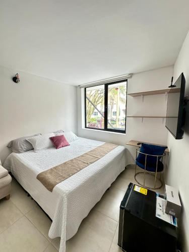 a white bedroom with a large bed and a window at Habitación 209 Luxury Laureles - Estadio in Medellín