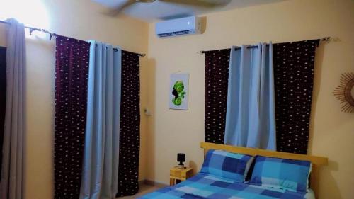 1 dormitorio con 1 cama con sábanas y cortinas azules en Studio privatif spacieux en air de plage, en Cotonou