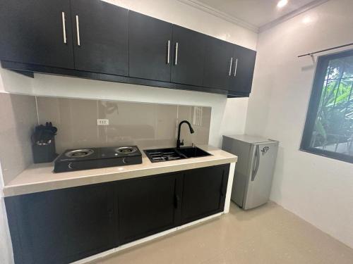 La cuisine est équipée de placards noirs, d'un évier et d'un réfrigérateur. dans l'établissement Casa Luna 4 by Angelito's, à General Luna