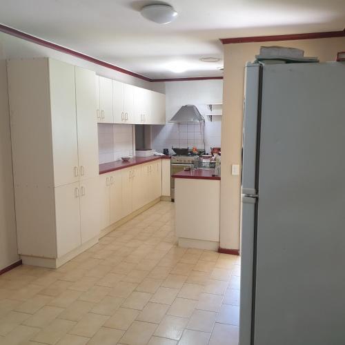 a kitchen with white cabinets and a refrigerator at Private room with shared facilities W in Werribee