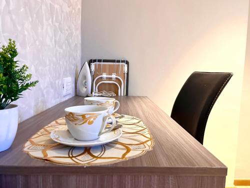 a wooden table with two cups and a plate on it at HillMark Suites in Ayer Keroh
