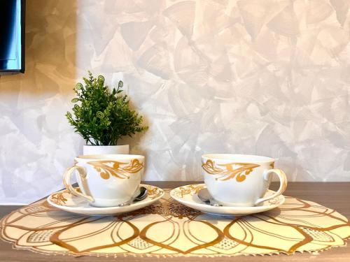 two tea cups and a potted plant on a table at HillMark Suites in Ayer Keroh