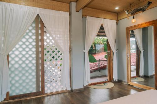 a room with two windows with white curtains at TỊNH Retreat Phu Quoc in Phu Quoc