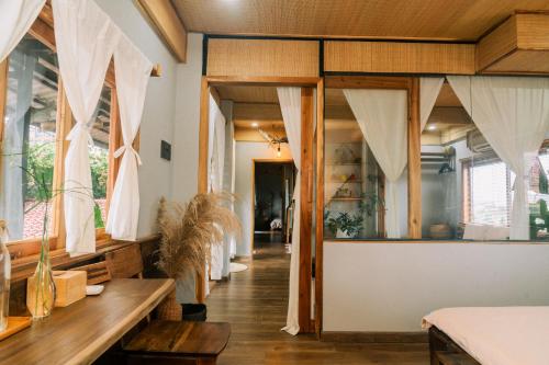 a room with large windows and wooden furniture at TỊNH Retreat Phu Quoc in Phu Quoc