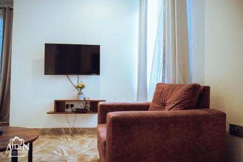 a living room with a chair and a flat screen tv at AIDEN HOMES AND APARTMENTS HOTEl in Koforidua