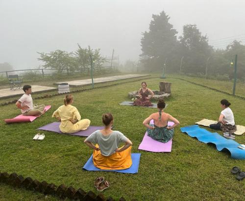 a group of people sitting in the grass doing yoga at Kunjapuri camps & Cottage in Narendranagar