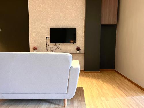 a living room with a white couch and a tv at HillMark Suites in Ayer Keroh
