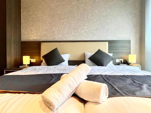 two beds in a hotel room with towels on them at HillMark Suites in Ayer Keroh